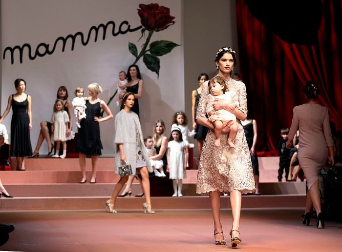 A model holding a child presents a creation from the Dolce & Gabbana Autumn/Winter 2015/16 collection during Milan Fashion Week