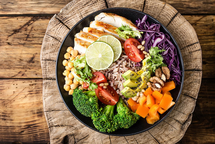Buddha bowl salad with chicken fillet, brown rice, avocado, pepper, tomato, broccoli, red cabbage, chickpea, fresh lettuce salad, pine nuts and walnuts. healthy food. balanced diet eating. Top view (Buddha bowl salad with chicken fillet, brown rice, a