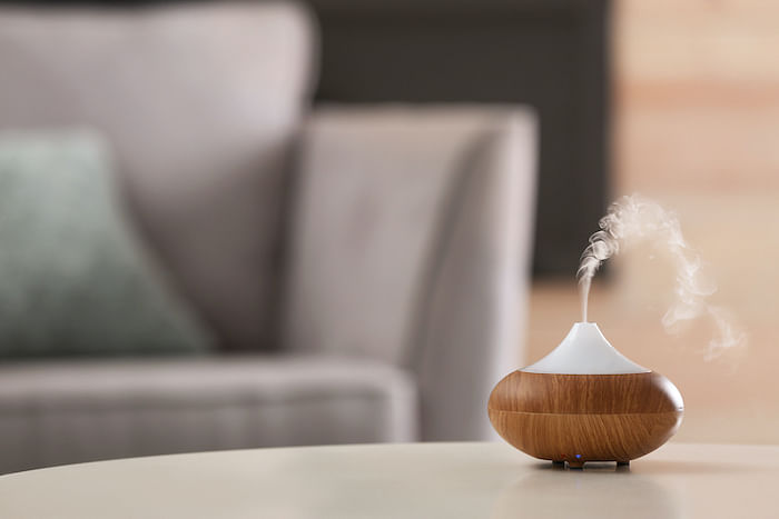 Aroma oil diffuser lamp on table against blurred background