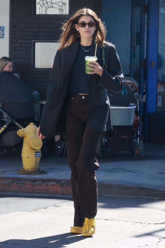 Kaia Gerber wears her yellow Onitsuka sneakers with an all-black outfit (and green juice).