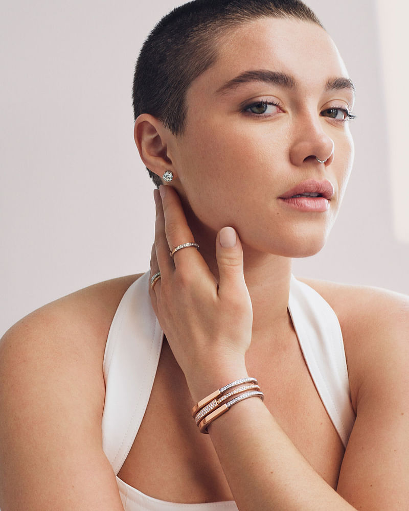 Florence Pugh wearing an assortment of Tiffany Lock rings and bangles in white gold and rose gold with diamonds; rose gold and diamond Tiffany Lock earring